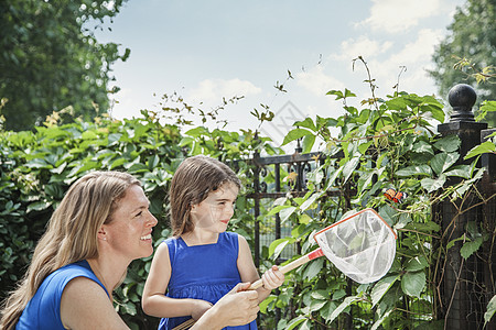 母亲和女儿带着蝴蝶微笑 并试图在花园中抓蝴蝶 (笑声)图片