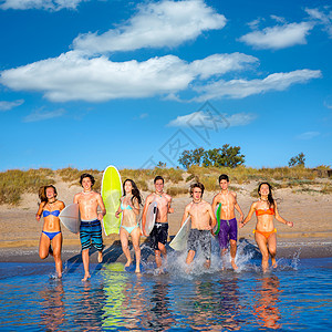 青少年冲浪者团体在海滩上喷水女性派对金发男性支撑蓝色朋友们女孩们跑步假期图片