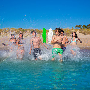 青少年冲浪者团体在海滩上喷水冲浪板女性海滨飞溅团队幸福金发朋友们运动波浪图片