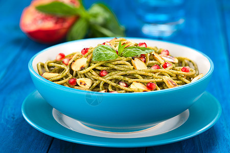 与Pesto Pomegralate和Almonds的意大利面条盘子水果石榴水平香蒜杏仁蓝色叶子烹饪草本植物图片