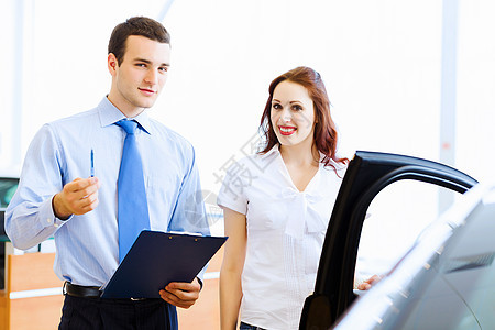 在汽车沙龙的年轻女子租赁推销员顾问销售合同经销商驾驶夫妻客户销售员图片