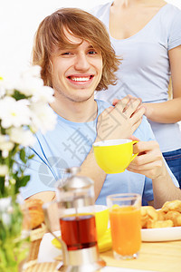 快乐的年轻人喝茶饮料微笑男性乐趣蓝色成人幸福杯子闲暇厨房图片