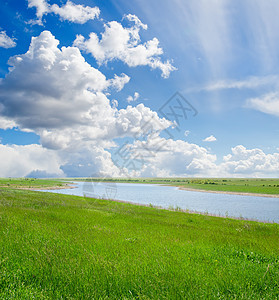 绿草和有江河的多云天空图片