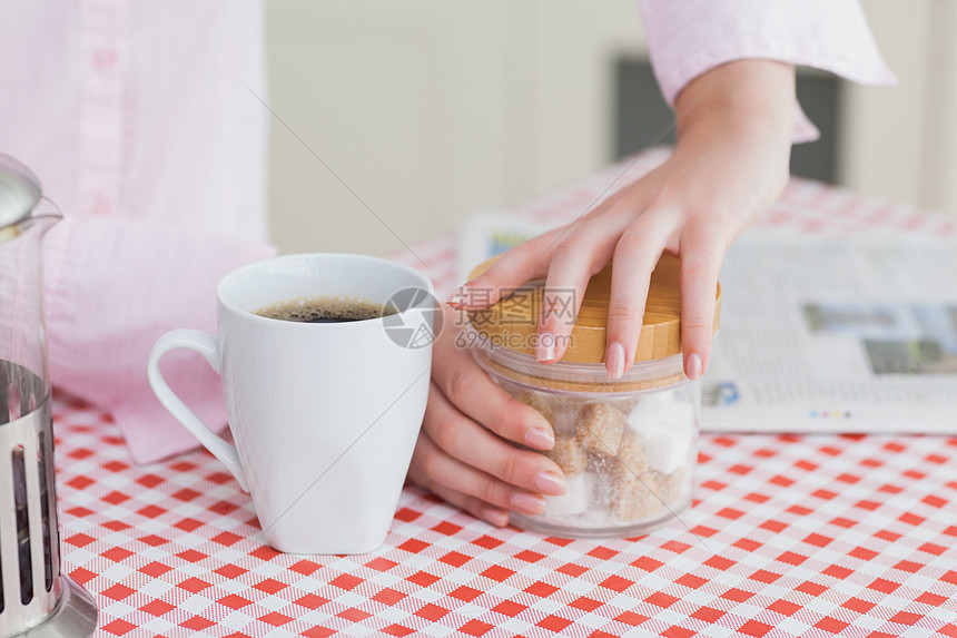 含咖啡杯和糖立方体容器的妇女图片