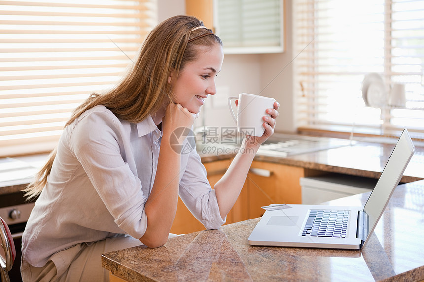 带着咖啡杯的快乐女人看着笔记本电脑图片