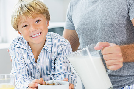 爸爸妈妈和孩子一起在微笑的男孩和父亲一起喂奶吃麦片背景