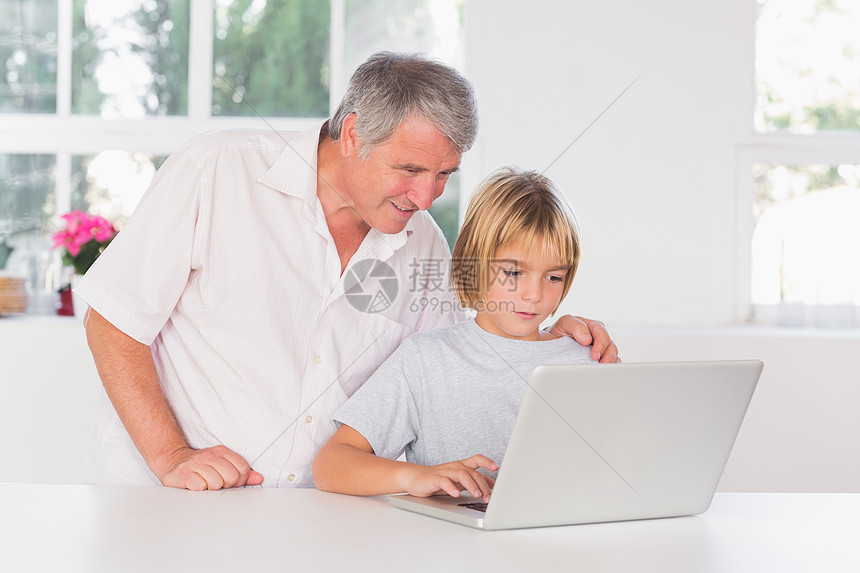 祖父和孩子笑着看笔记本电脑图片
