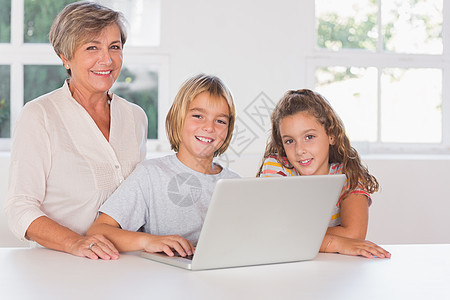 外祖母和孩子们看镜头 前方还有笔记本电脑图片