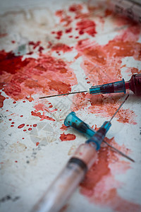 两支注射器躺在血溅着的血滴子上背景图片