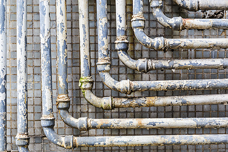 墙上一系列平行的旧管线线条金属关节基础设施建筑对角线管道导管间距灰色图片