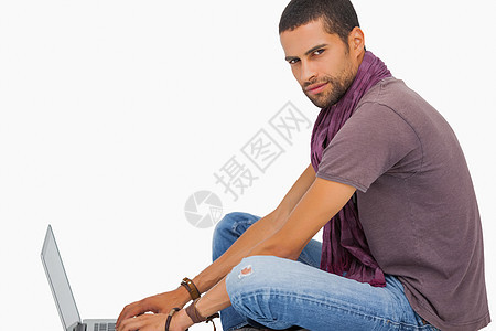 使用笔记本电脑坐在地板上 身着围巾的严肃男子图片