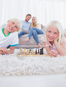 躺在地毯上玩象棋的儿童图片