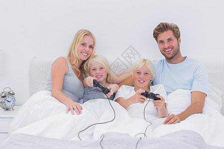 玩电子游戏的家庭乐趣坐垫短发母亲微笑游戏卧室羽绒被枕头男性图片