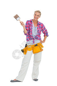 戴着工具带的拿着油漆刷子的快乐女人图片