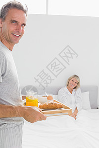 快乐的男人把早餐在床上带给他的搭档图片