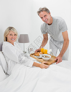 快乐的男人在床上给搭档吃早饭图片