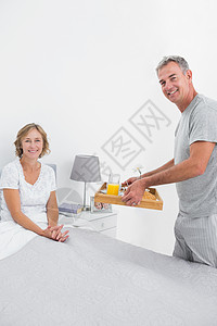 微笑的丈夫 带早餐到床上去给妻子吃图片