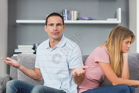 在沙发上和男人对着镜头 拳打脚踢后 一对坐在背对背的情侣坐在一起图片