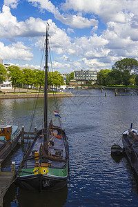 停靠在阿姆斯特丹海岸附近的船舶房子驳船窗户海滨蓝色多云运输码头倾倒桅杆图片