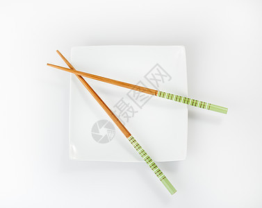 在白色背景上被孤立的板块上的筷子绿色盘子餐具图片