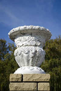 返工古老的石膏园花瓶 在树背上的现代砖头上背景
