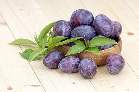 紫色水果碗里的新鲜李子食欲宏观食物甜点水果饮食紫色木头小吃叶子背景
