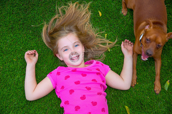 躺在草地上微笑的美丽金发女孩女孩孩子婴儿宠物说谎童年幸福友谊快乐吉祥物后院图片