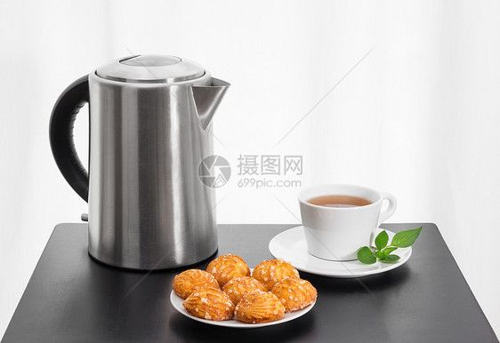 电水壶 茶杯和餐桌上的饼干图片