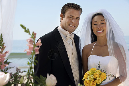 快乐新娘和新郎的肖像 用鲜花对抗大海图片