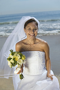 带着花束在海滩上微笑的新娘(肖像)图片
