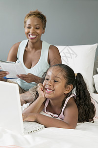 母亲和女儿在床上看笔记本电脑图片