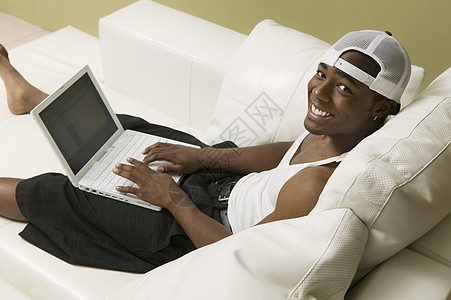 沙发上年轻男子使用笔记本电脑高角度视图肖像图片