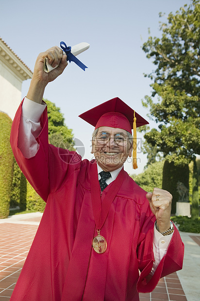 身着毕业服装持有学位的一位兴奋的高级男子的肖像图片