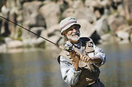 一个快乐的西班牙裔老人在阳光明媚的一天钓鱼的肖像图片
