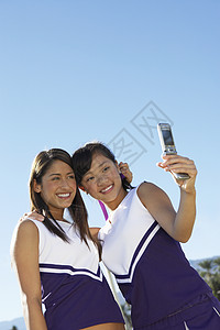 与队友通过手机拍照的亚洲啦啦队队员欢乐图片