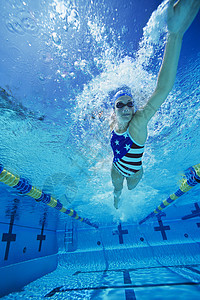 一位在水下游泳的年轻女子的低角度视角图片