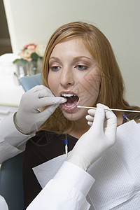 在诊所检查女性病人牙齿的牙科医生;图片