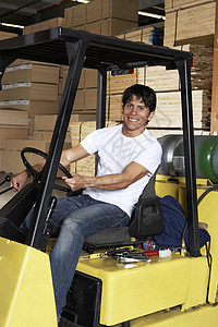 一名快乐的中年成年人在仓库驾驶叉式搬运车的肖像图片