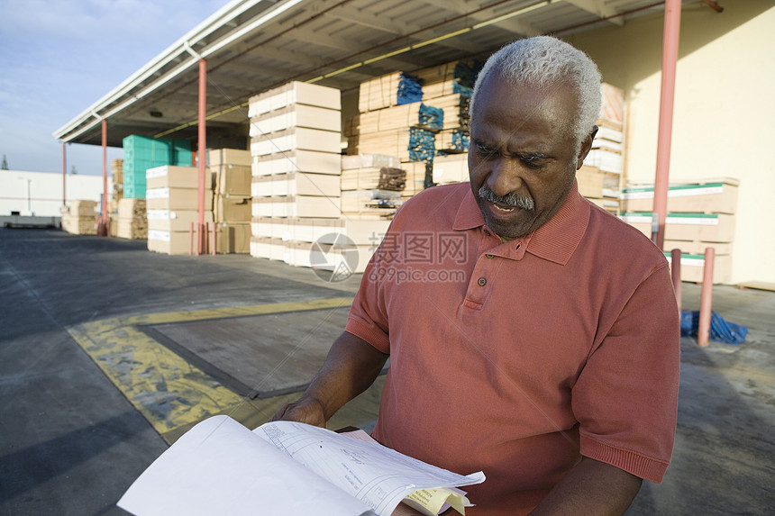 阅读文件的非裔美国高级男性仓库工人图片