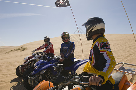 三个人骑在沙漠中的四重车图片