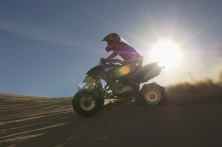 年轻人在沙漠中骑着四重车图片