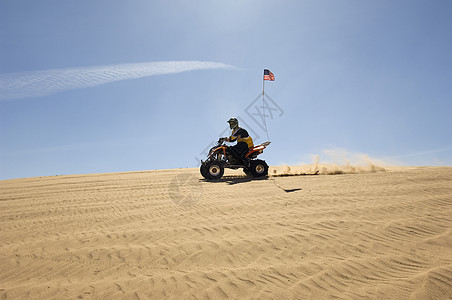 一个男人在阳光明媚的白天 在沙漠中骑四轮自行车的侧面景色灰尘乐趣地形司机娱乐冒险男人晴天人间运动图片