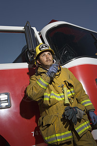 一个消防员在无线电上说话时 低角度的视角背景是消防车图片
