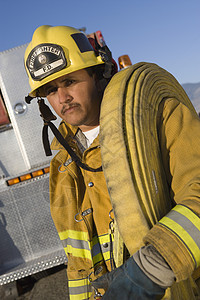 一名肩扛着消防水管的消防战士的肖像图片