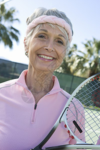 在法庭上一位快乐的高级女性网球运动员的肖像图片