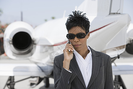 自信的女商务人士在机场使用带飞机的手机图片