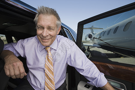 一位快乐的高级商务人士从机场的汽车下楼的肖像图片