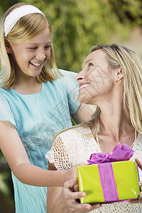 快乐的少女女儿在母亲生日时送礼物给母亲图片