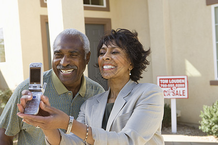 美籍非裔夫妇在新房子前通过手机进行自画像的自我肖像图片