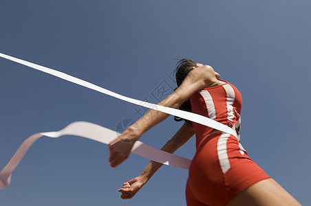 年轻女运动员在晴蓝天空中穿越终点线的低角度视角视图丝带优胜者运动赛跑者成人女性蓝色胜利阳光运动服图片